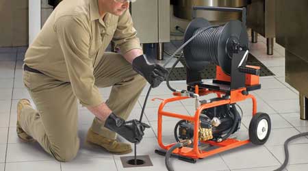 Image of a man cleaning a drain pipe with a professional machine